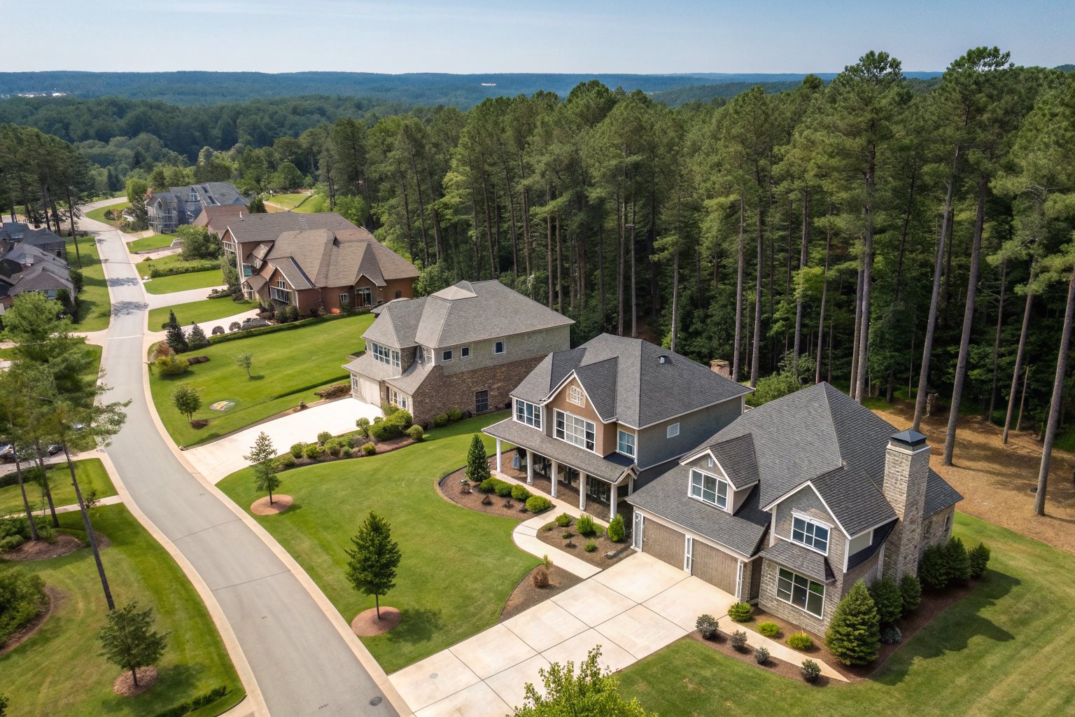 Aerial view of two-story homes with shingle roofs on curving cul-de-sacs surrounded by pines